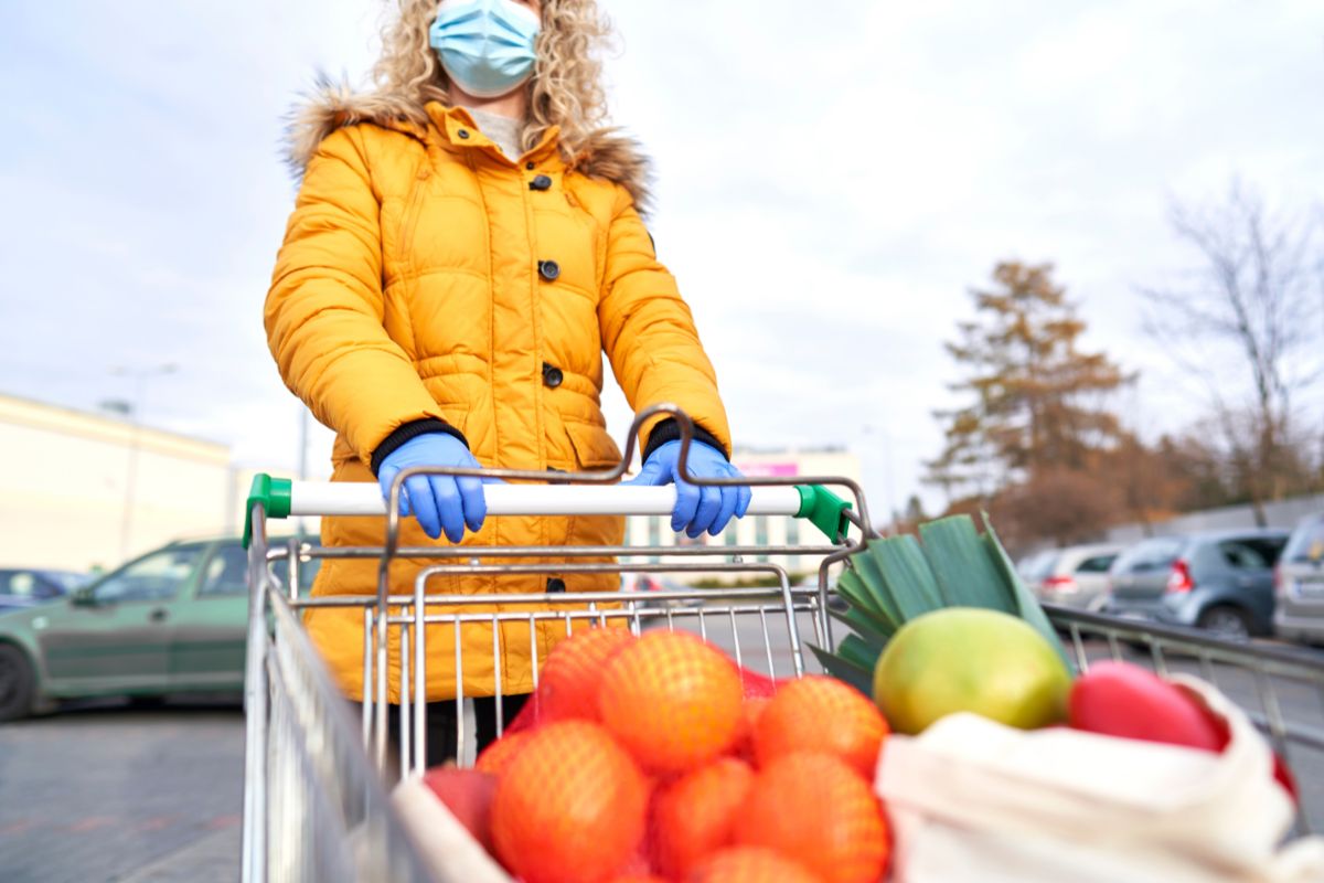 Woman in parka pushing a grocery cart.