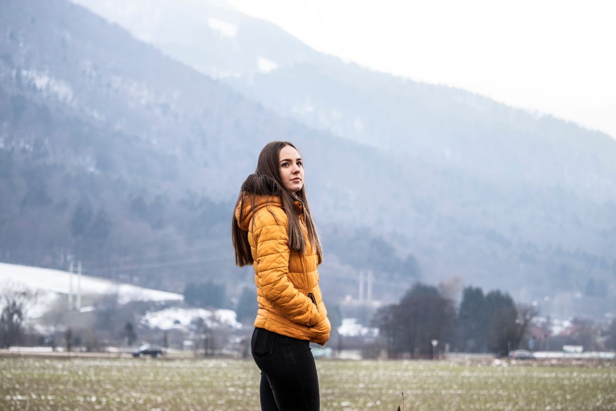 Photo of a woman wearing yellow puffer jacket.