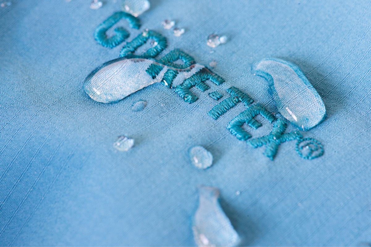 A piece of waterproof textile with the Gore-Tex logo repels raindrops, showing how effective the fabric is for staying dry.