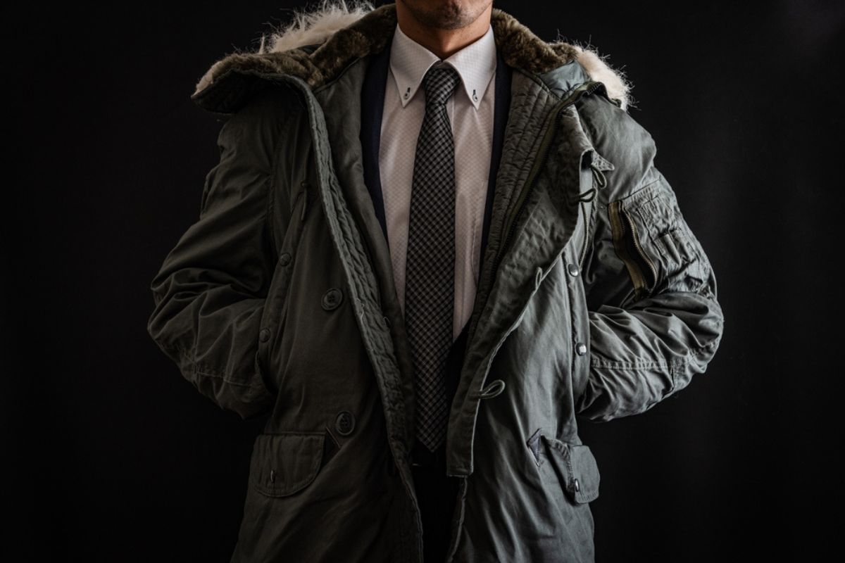 A man in black background wearing parka with suit.