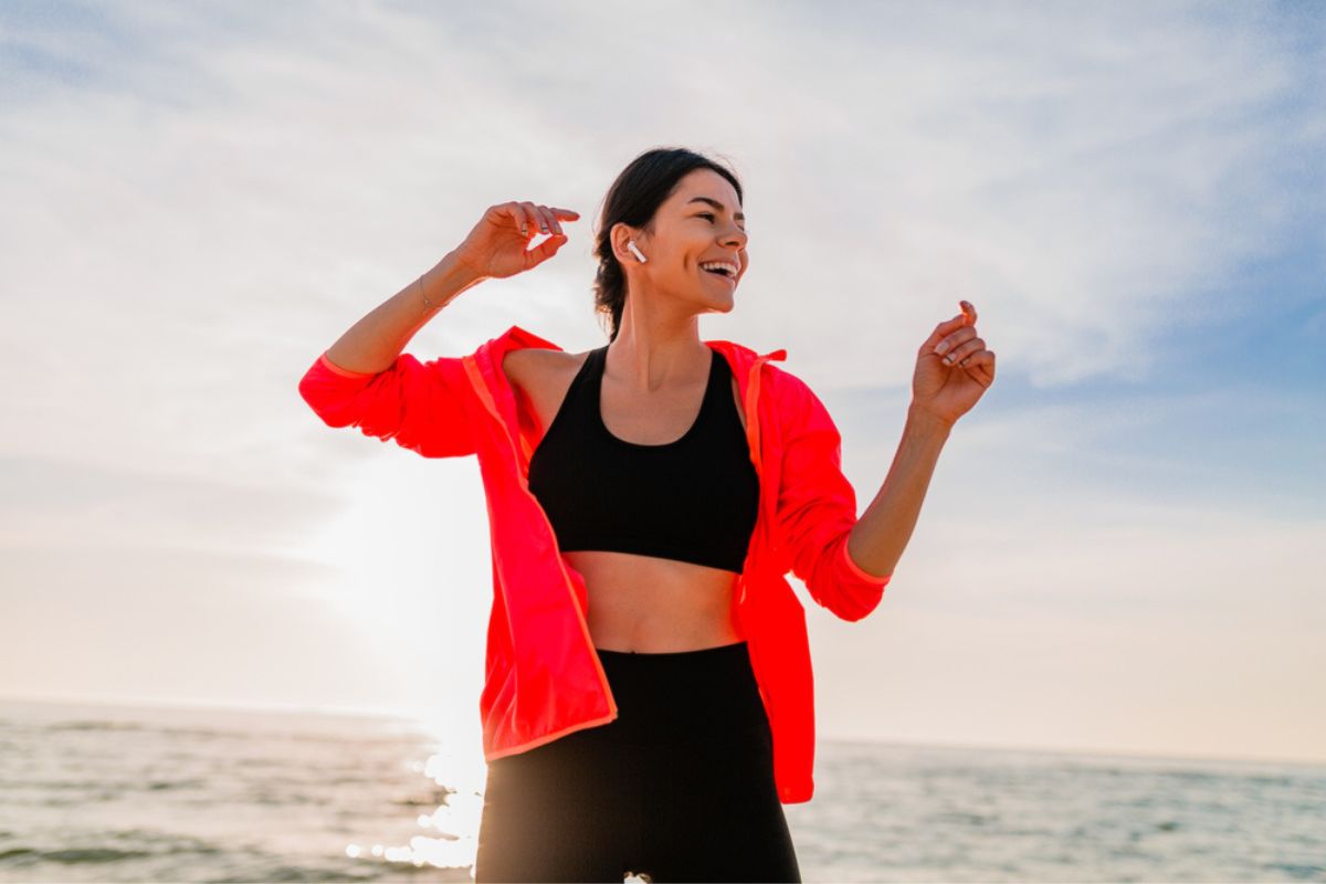 A happy woman wearing a windbreaker jacket at the beach.