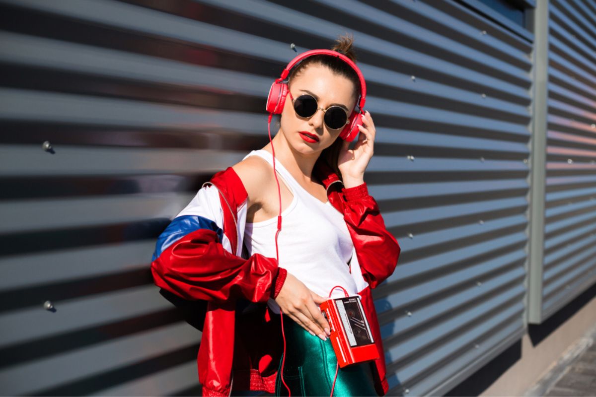Stylish girl in retro jacket and vintage cassette player listens to music, fashion trends, entertainment, heat in summer