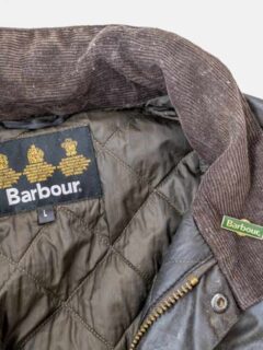 Traditonal classic Barbour waxed jacket selectective focus on the brand name lapel badge.